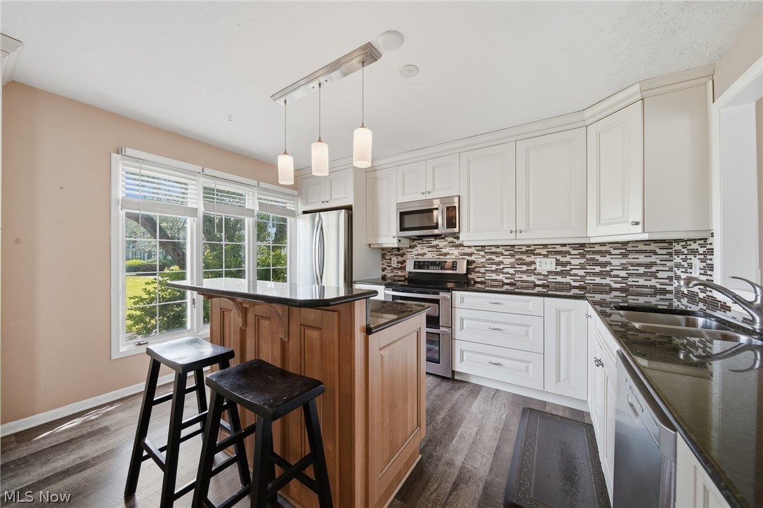 824 South Chillicothe Road, Unit 2 Aurora, OH 44202 - Photo 5 of 42 Open-concept kitchen featuring white cabinetry, dark stone countertops, stainless steel appliances, and wood-finish flooring