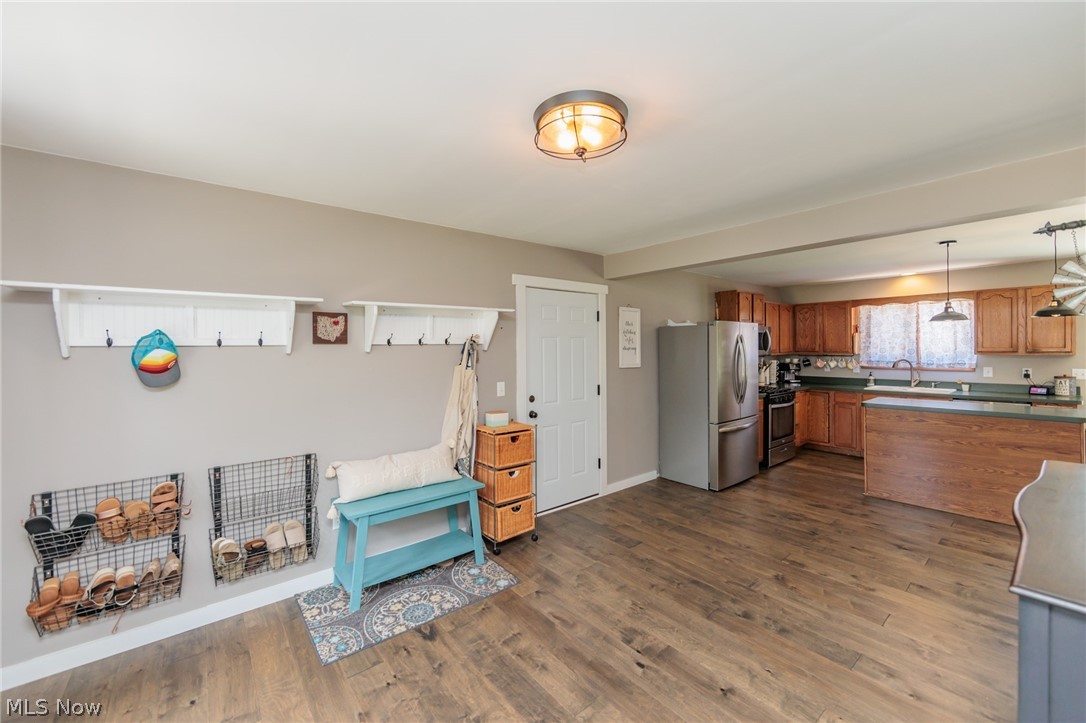 Kitchen with decorative light fixtures, range, hardwood / wood-style floors, stainless steel fridge, and sink