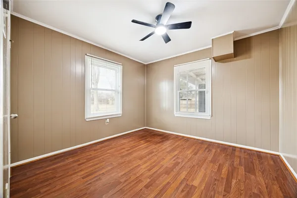 a view of empty room with wooden floor and fan