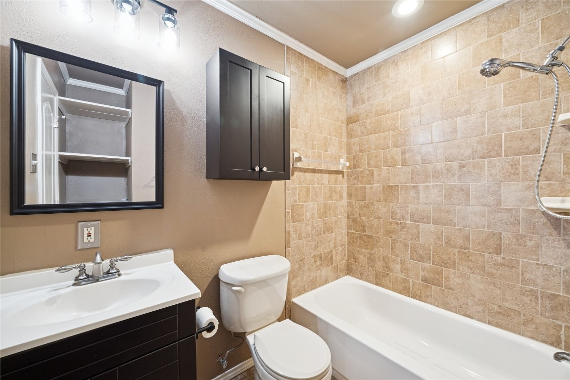 12537 Terrance Street Houston, TX 77085 - Photo 16 of 27 This bathroom features a modern vanity with a mirror, and a combination shower-tub. The space includes a wall-mounted cabinet for storage, creating a clean and functional area.