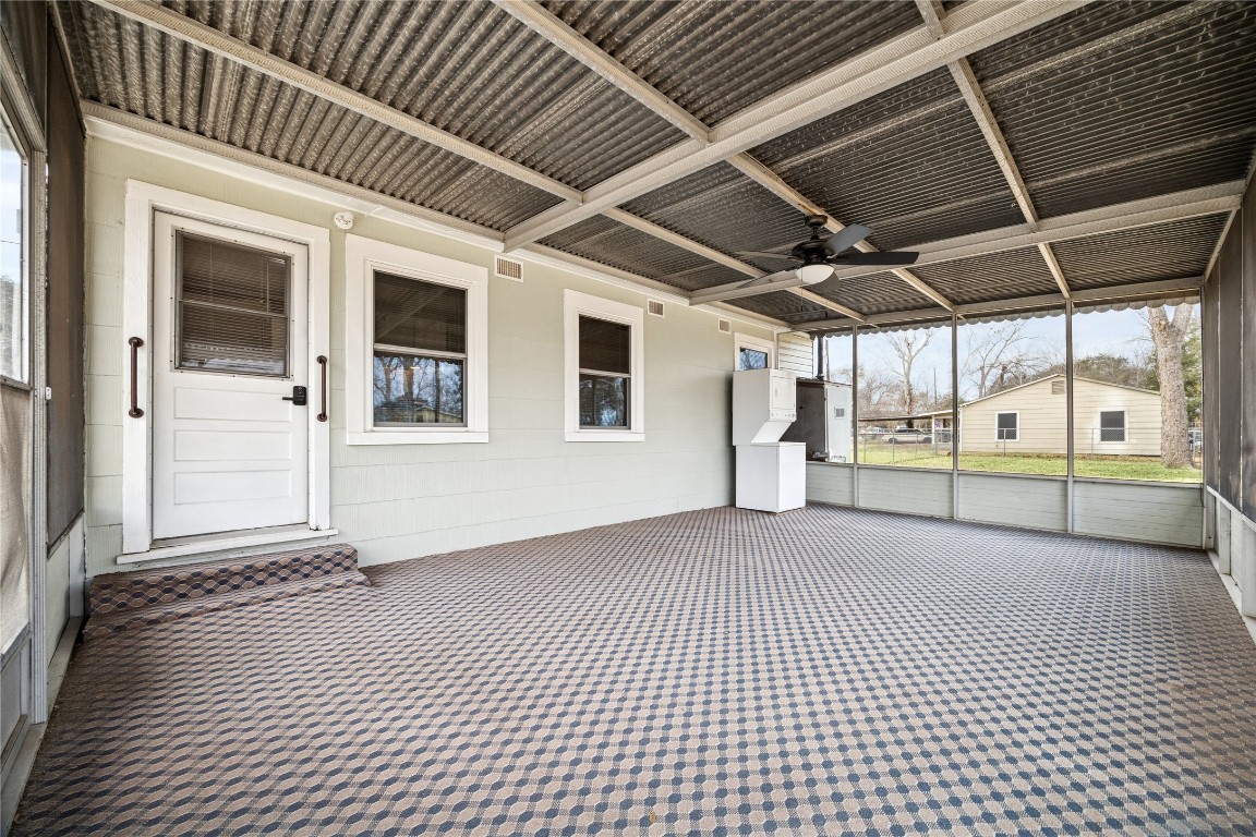 12537 Terrance Street Houston, TX 77085 - Photo 19 of 27 From this spacious screened-in porch with carpeted flooring and ceiling fan you will have access to a grassy backyard. It features a utility area with a washer and dryer, offering a versatile space for relaxation and functionality.