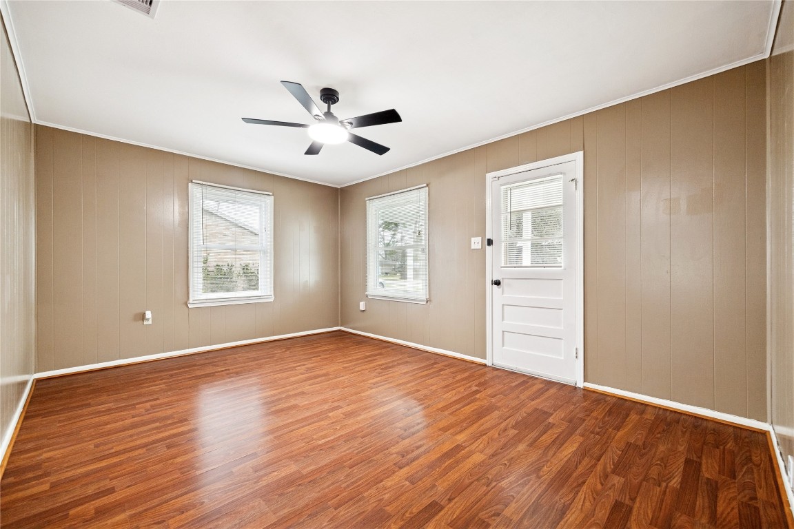 12537 Terrance Street Houston, TX 77085 - Photo 5 of 27 The living room has tan paneled walls, and ample natural light from two windows. It has a modern ceiling fan and laminate flooring providing a cozy and functional space.
