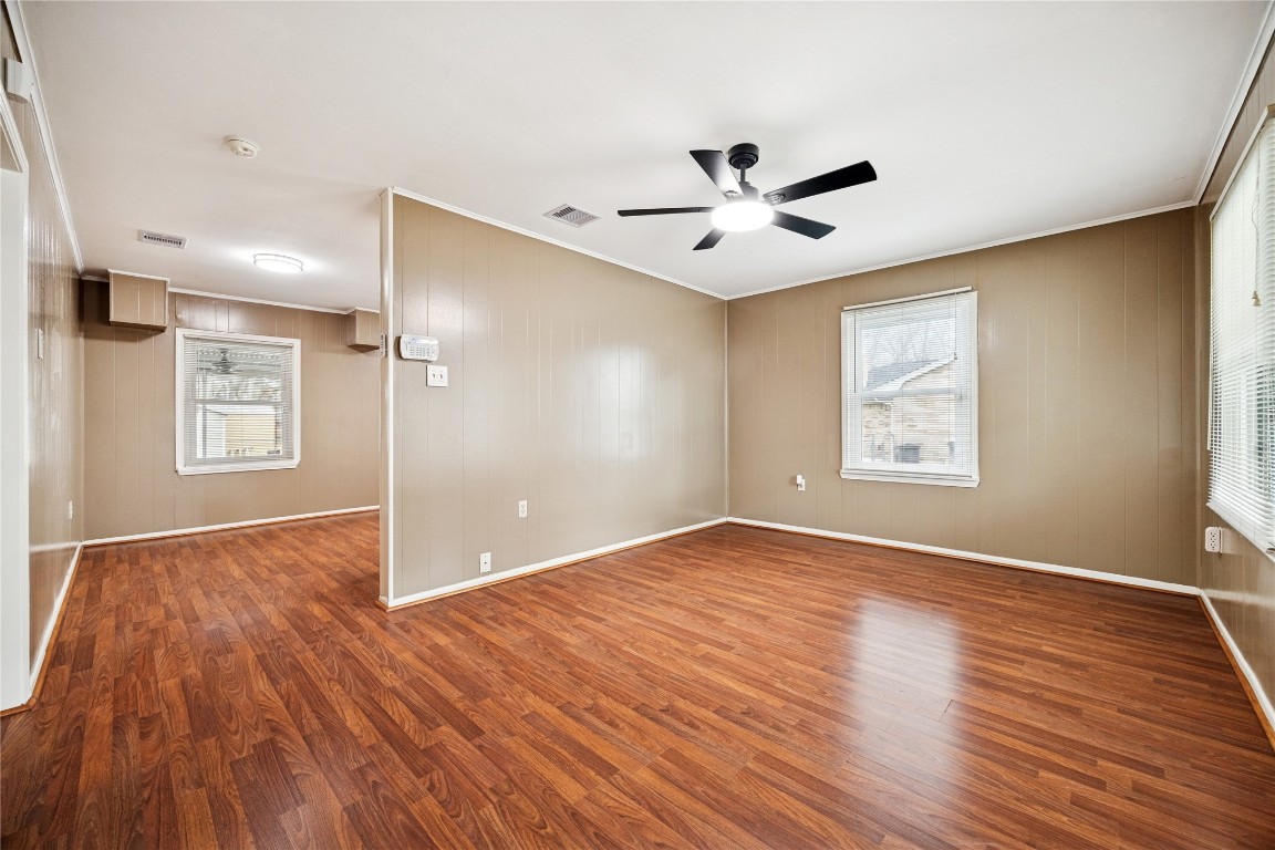 12537 Terrance Street Houston, TX 77085 - Photo 8 of 27 The spacious living room with warm wood laminate flooring and neutral walls, featuring large windows for natural light and a ceiling fan for comfort.