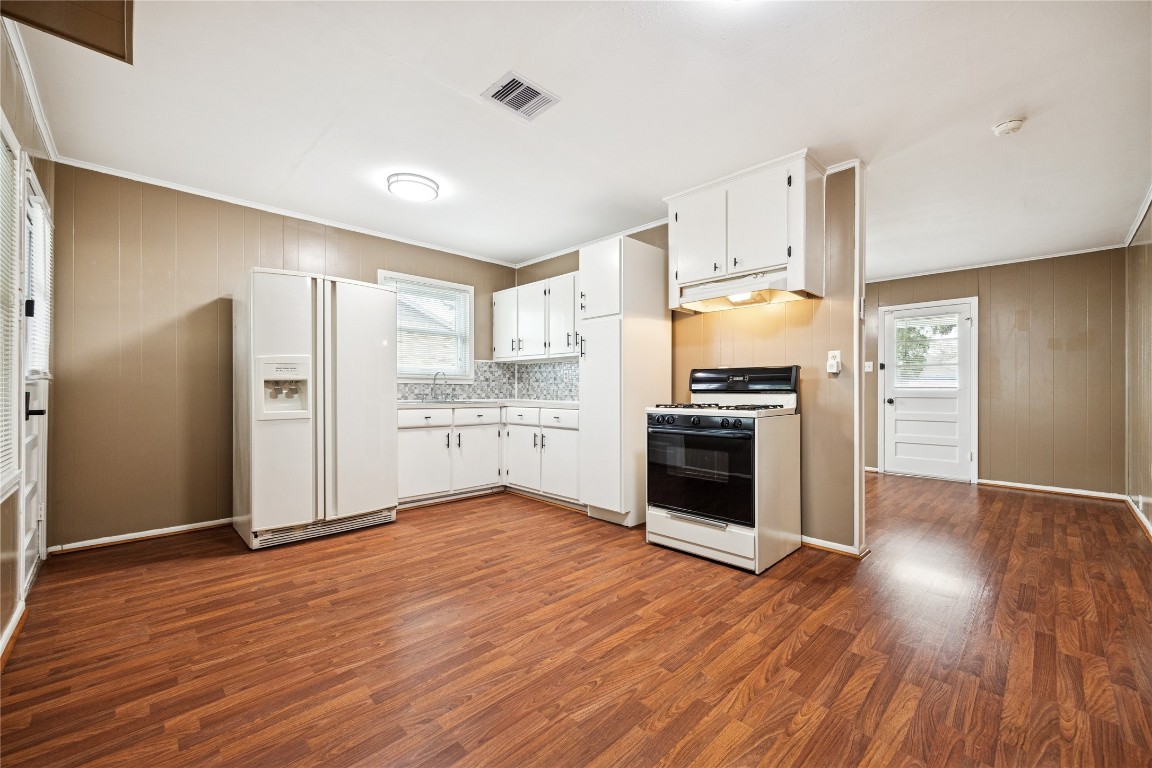 12537 Terrance Street Houston, TX 77085 - Photo 9 of 27 This kitchen features laminate flooring, white cabinetry, and neutral-toned walls. It includes a gas stove, and ample counter space. The room is well-lit with overhead lighting and windows, offering a spacious and inviting atmosphere.