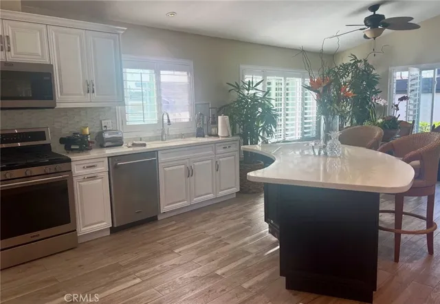 a kitchen with stainless steel appliances granite countertop a stove a refrigerator a sink a dining table and chairs