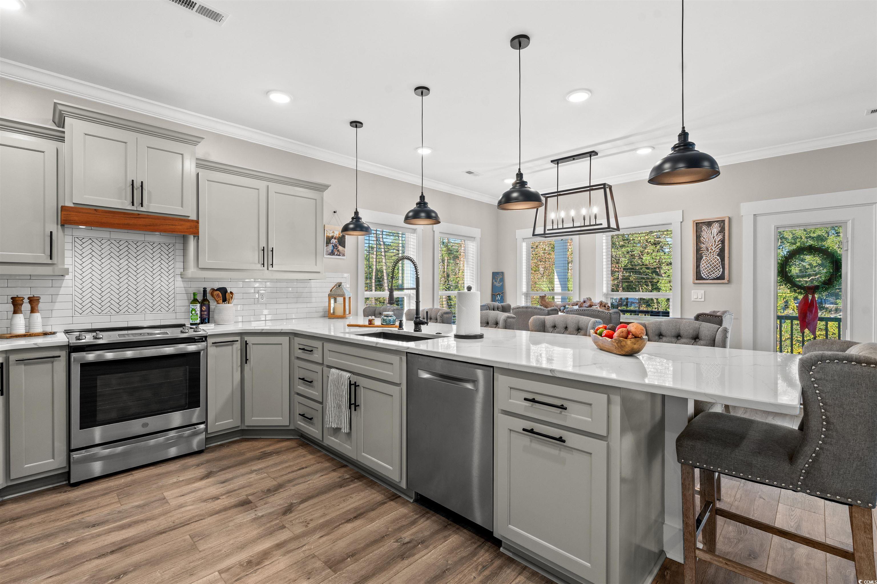 355 Oak Avenue Murrells Inlet, SC 29576 - Photo 16 of 34 Kitchen with a peninsula, a sink, wood finished floors, gray cabinetry, and appliances with stainless steel finishes
