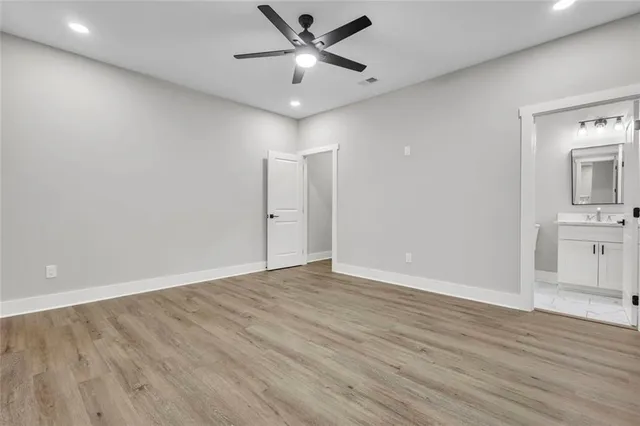 an empty room with wooden floor and a ceiling fan
