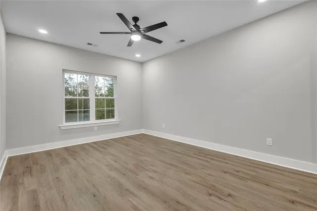 an empty room with wooden floor and windows
