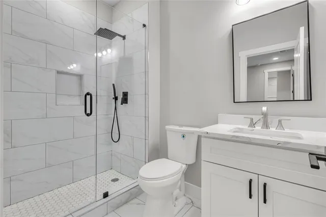 a bathroom with a shower sink vanity mirror and toilet