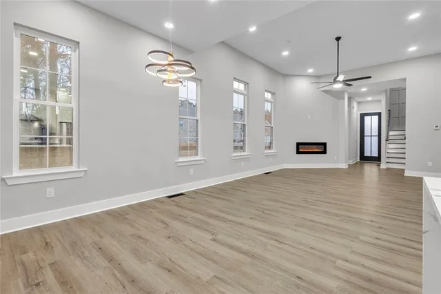 an empty room with wooden floor chandelier and windows