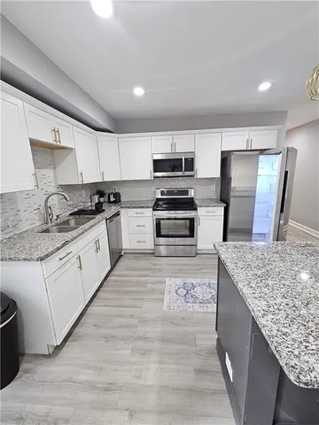 a kitchen with stainless steel appliances granite countertop a kitchen island a stove a refrigerator and a sink