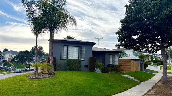 a front view of a house with a garden and trees