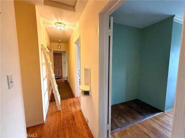 a view of a hallway with wooden floor and a bathroom