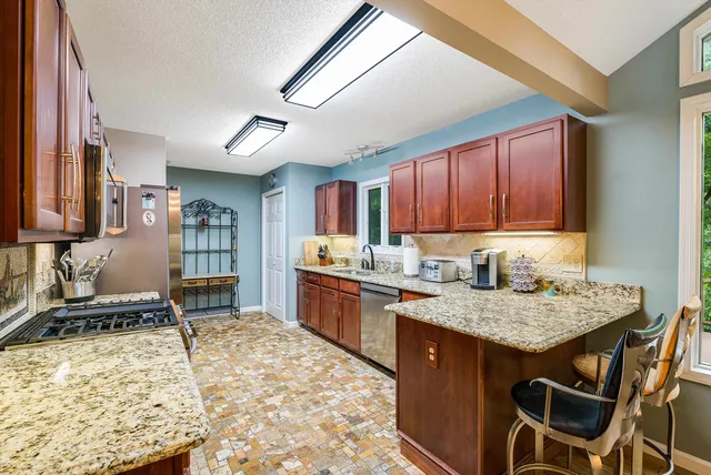 a kitchen with granite countertop cabinets stainless steel appliances and a wooden floor