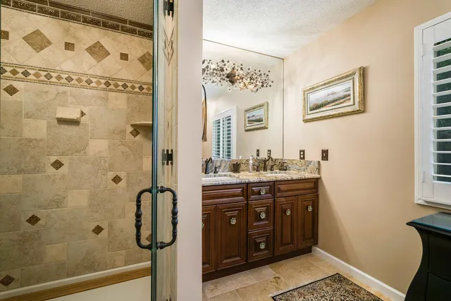 a bathroom with a granite countertop sink and a shower