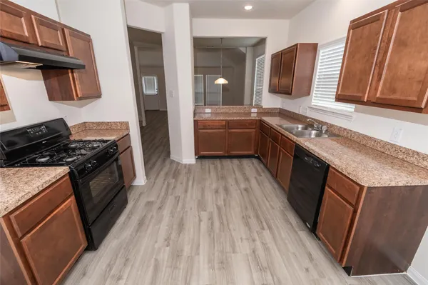 a kitchen with stainless steel appliances granite countertop wooden cabinets a stove top oven a sink and dishwasher
