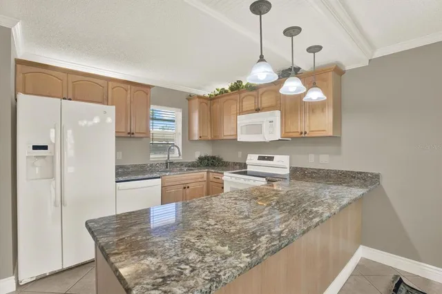 a kitchen with granite countertop cabinets a refrigerator a sink and a stove