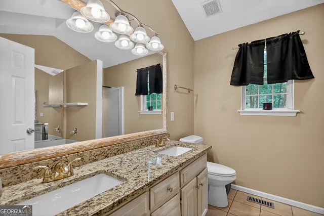 a bathroom with a granite countertop sink a toilet and mirror