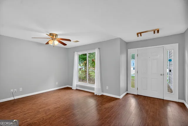 a view of empty room with wooden floor and fan
