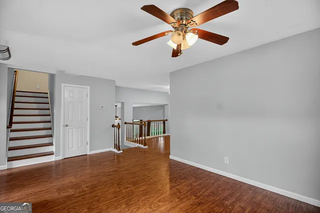 an empty room with wooden floor and a ceiling fan