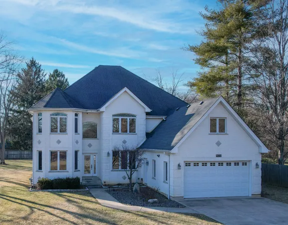 a view of a big house with wooden fence and large trees