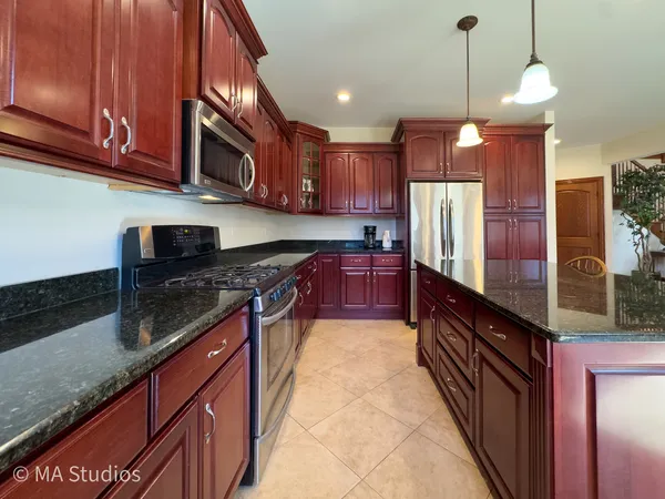 a large kitchen with stainless steel appliances granite countertop a stove a sink and a microwave