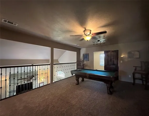 a living room with furniture pool table and a ceiling fan