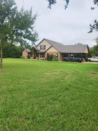 a front view of a house with a garden and trees