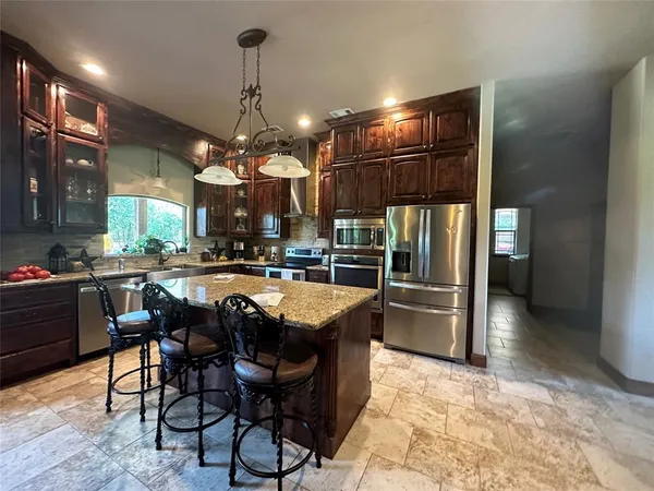 a kitchen with stainless steel appliances granite countertop a sink a stove and a refrigerator
