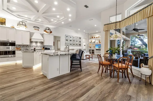 a open kitchen with stainless steel appliances granite countertop a stove top oven a dining table and chairs with wooden floor