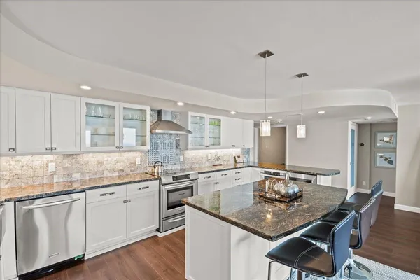 a kitchen with center island white cabinets and refrigerator