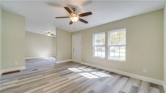 a view of an empty room with wooden floor and a window