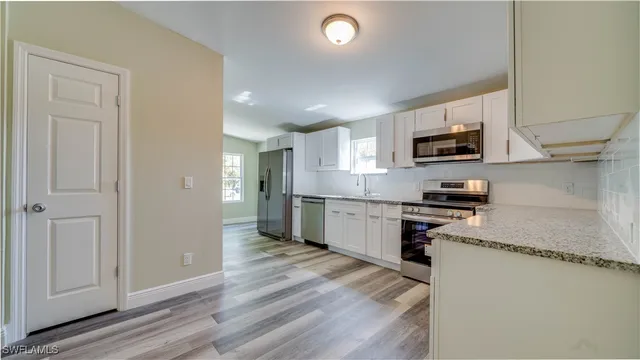 a kitchen with stainless steel appliances granite countertop a refrigerator a stove top oven a sink and dishwasher