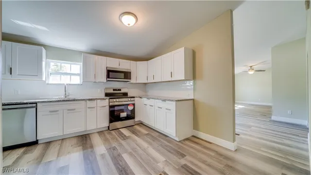 a kitchen with granite countertop white cabinets and stainless steel appliances