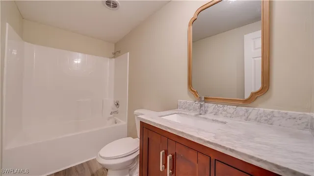 a bathroom with a granite countertop sink a toilet and shower