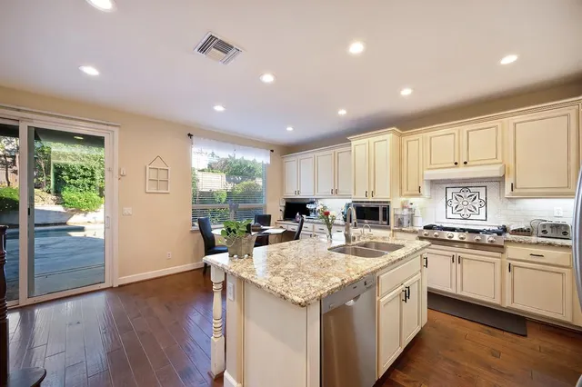 a kitchen with granite countertop a sink a stove and cabinets