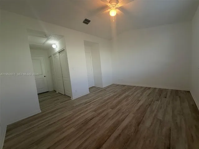 an empty room with wooden floor and fan