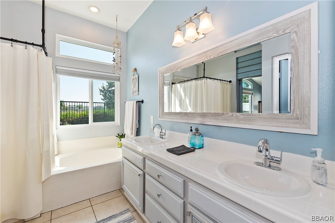 2201 Wagon Train Street Corona, CA 92878 - Photo 11 of 24 a bathroom with a sink a vanity a mirror and a bathtub next to a window