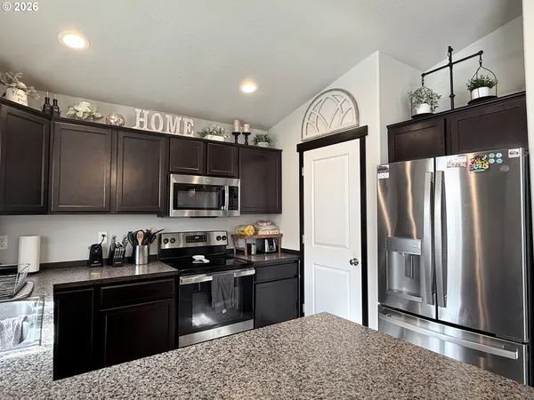 a kitchen with stainless steel appliances granite countertop a refrigerator a stove a sink and a microwave