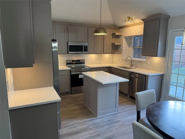 a kitchen with stainless steel appliances a table chairs sink and stove