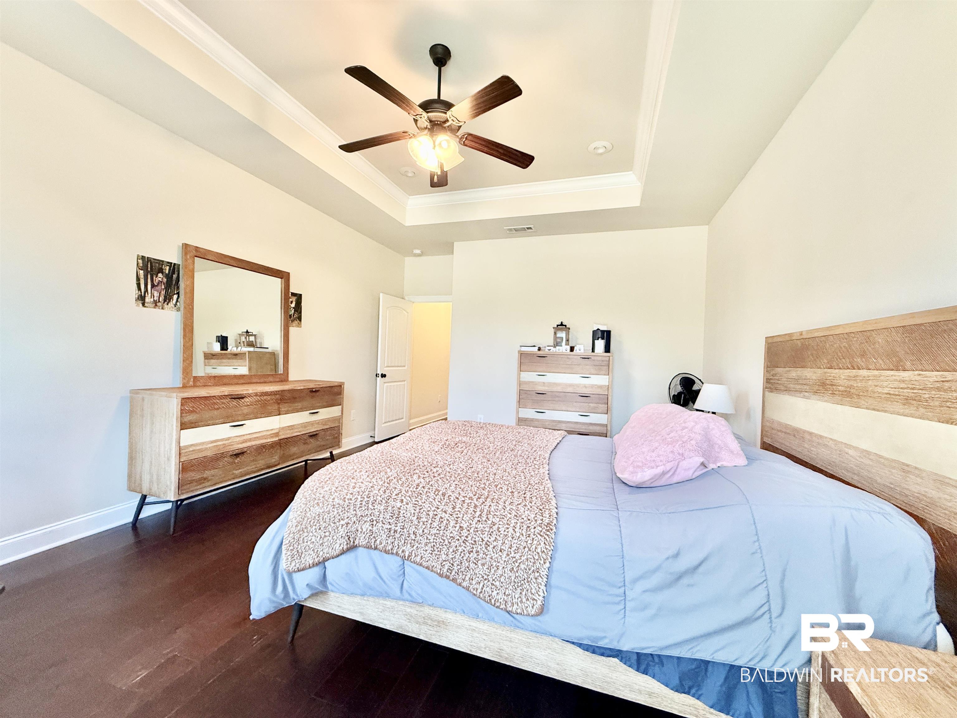 7011 Rocky Rd Loop Gulf Shores, AL 36542 - Photo 24 of 66 Bedroom with dark wood-type flooring, crown molding, ceiling fan, and a tray ceiling