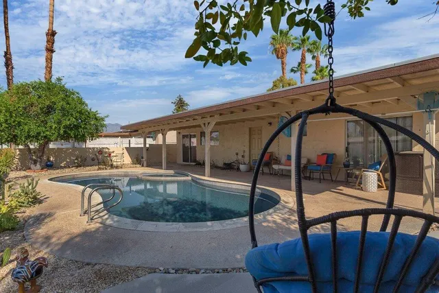 a view of a white house with a swimming pool and sitting area