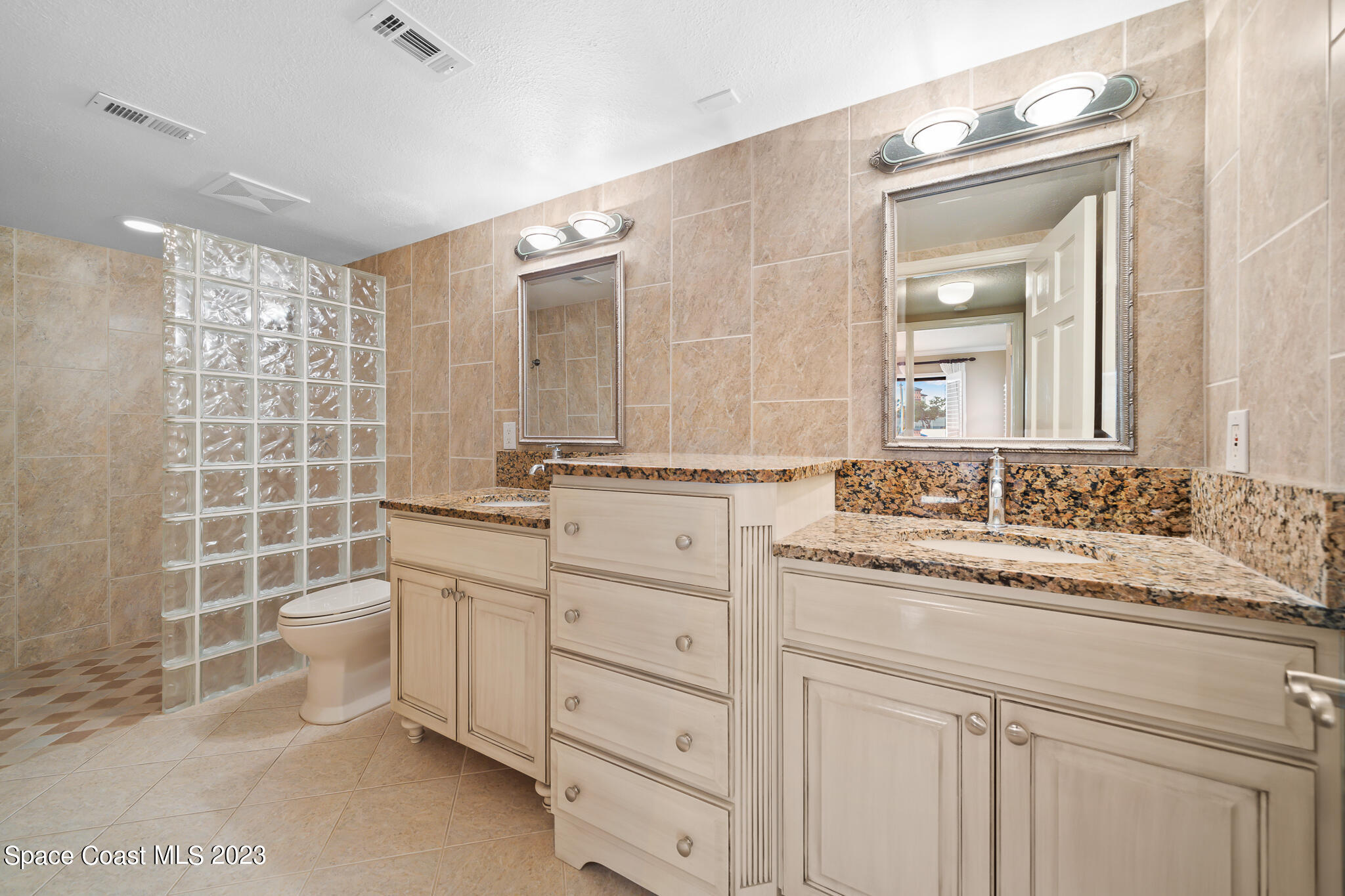 2220 Front Street, Unit 303 Melbourne, FL 32901 - Photo 20 of 24 a bathroom with a double vanity sink a toilet and a mirror