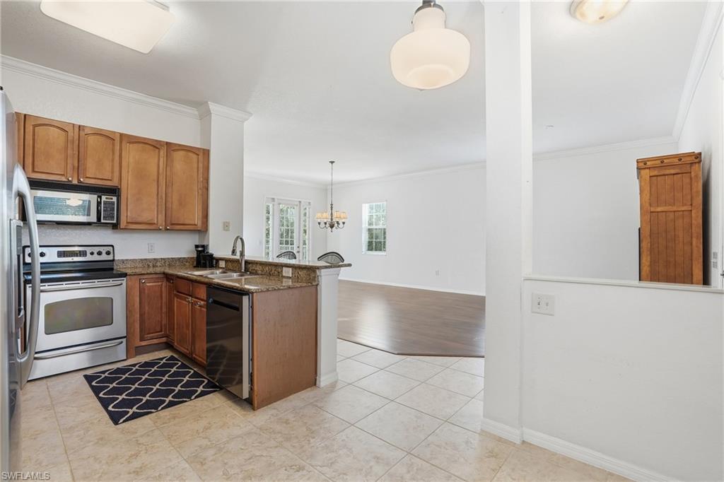 970 Peggy Circle, Unit 604 Naples, FL 34113 - Photo 13 of 24 Kitchen featuring appliances with stainless steel finishes, pendant lighting, crown molding, brown cabinetry, and a peninsula