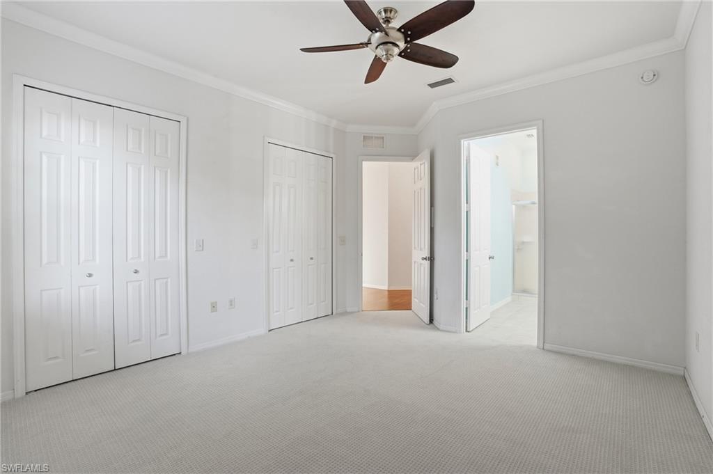 970 Peggy Circle, Unit 604 Naples, FL 34113 - Photo 18 of 24 Unfurnished bedroom with two closets, crown molding, carpet, ceiling fan, and connected bathroom