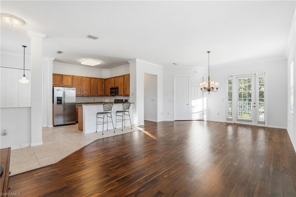 970 Peggy Circle, Unit 604 Naples, FL 34113 - Photo 5 of 24 Unfurnished living room with ornamental molding, light wood-type flooring, and a chandelier