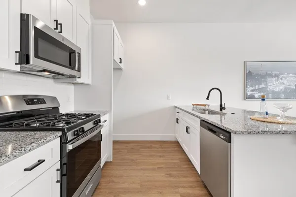 a kitchen with granite countertop a sink stainless steel appliances and cabinets