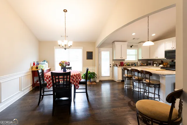 a view of a dining room and livingroom with furniture wooden floor a chandelier