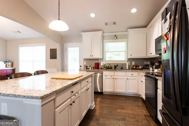 a kitchen with granite countertop kitchen island white cabinets and refrigerator