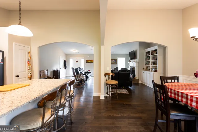 a dining room with wooden floor a chandelier a wooden table and chairs